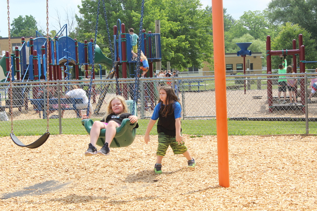 a student pushing another student on the swings