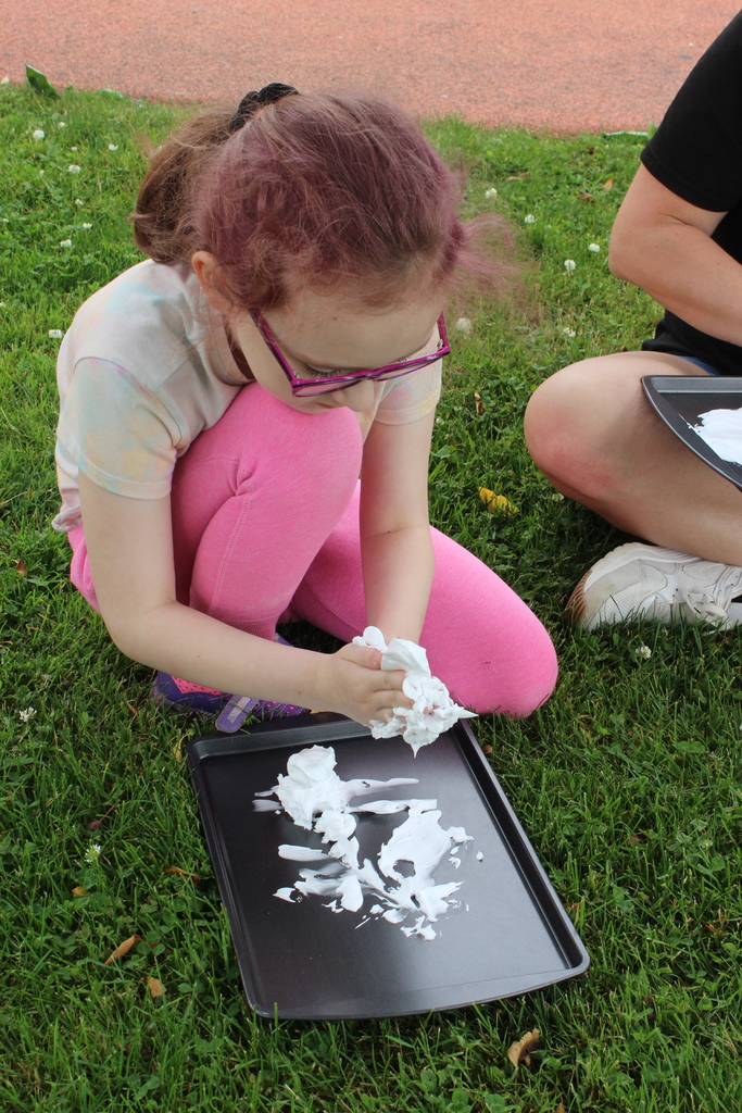 girl playing with shaving cream on a tray