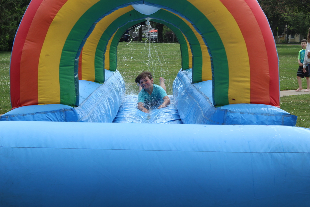 boy sliding through on rainbow water slide