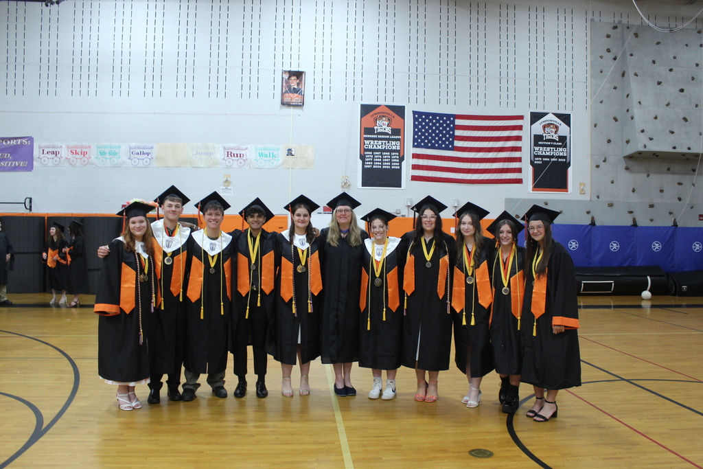 students in graduation gowns and caps standing with teacher