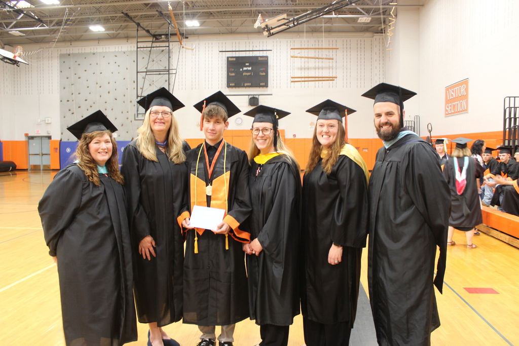 faculty standing with graduating senior in caps and gowns