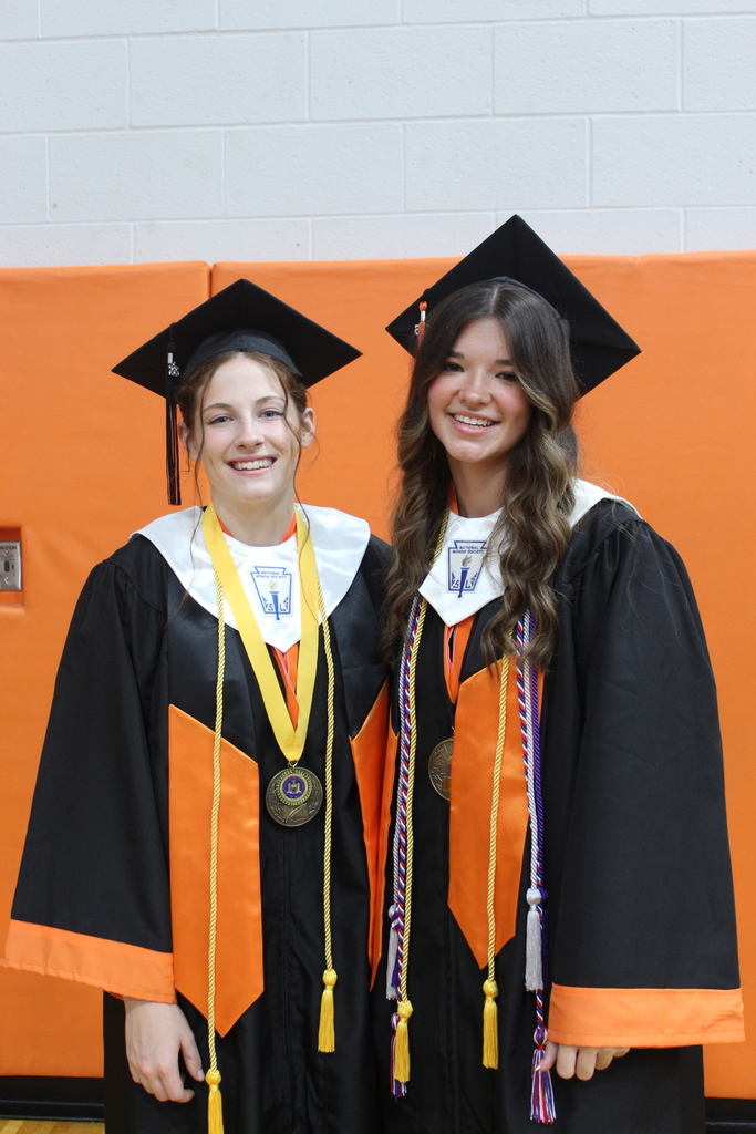 two girls standing next to each other in caps and gowns