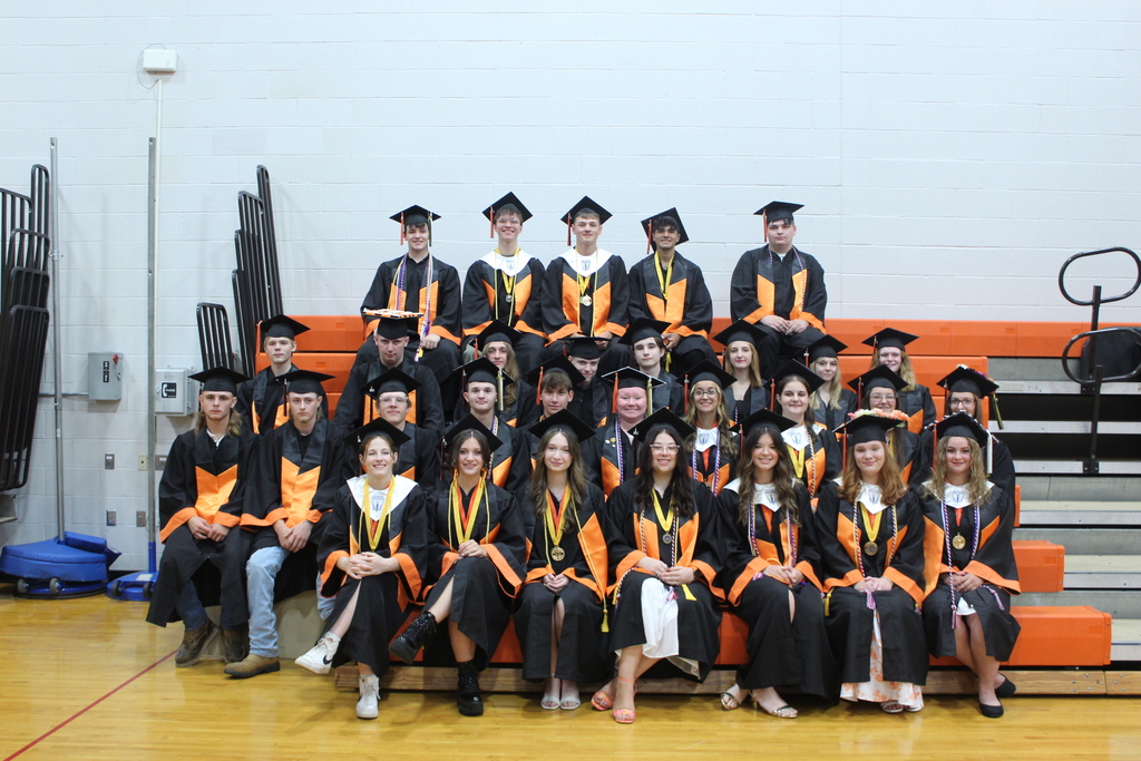 seniors sitting on bleachers in caps and gowns