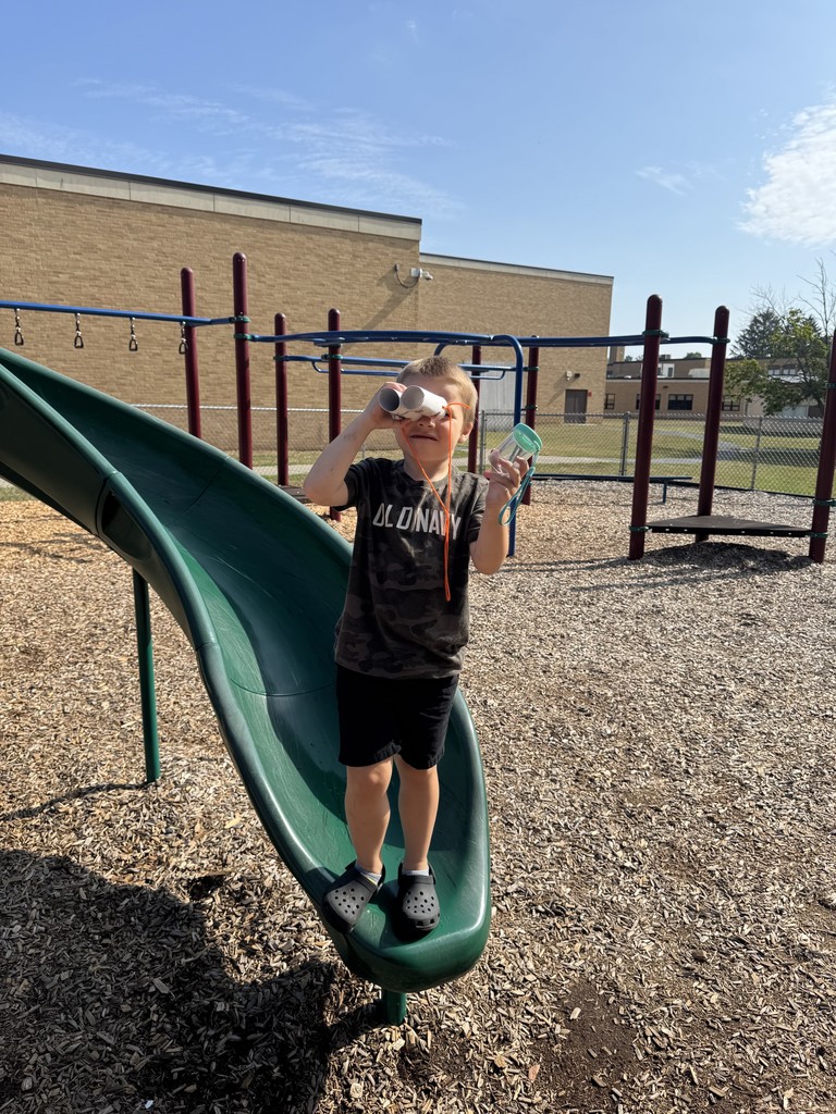 boy standing on slide using binoculars