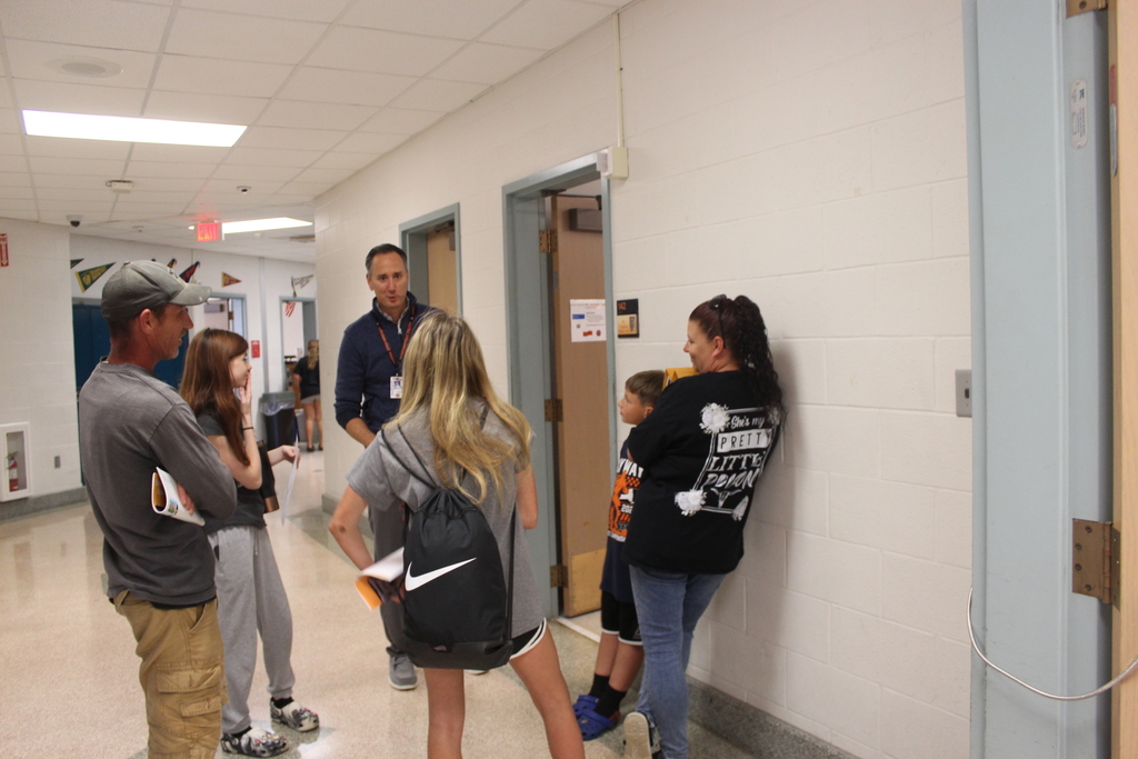 people standing talking to teacher in hallway