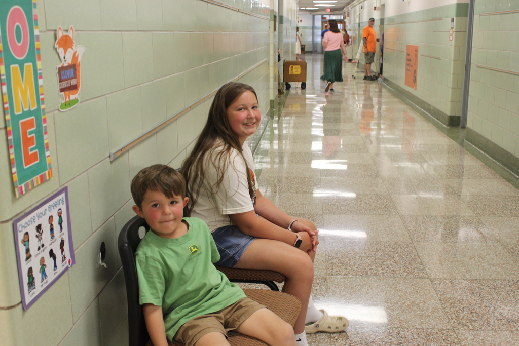boy and girl sitting in chairs outside classroom