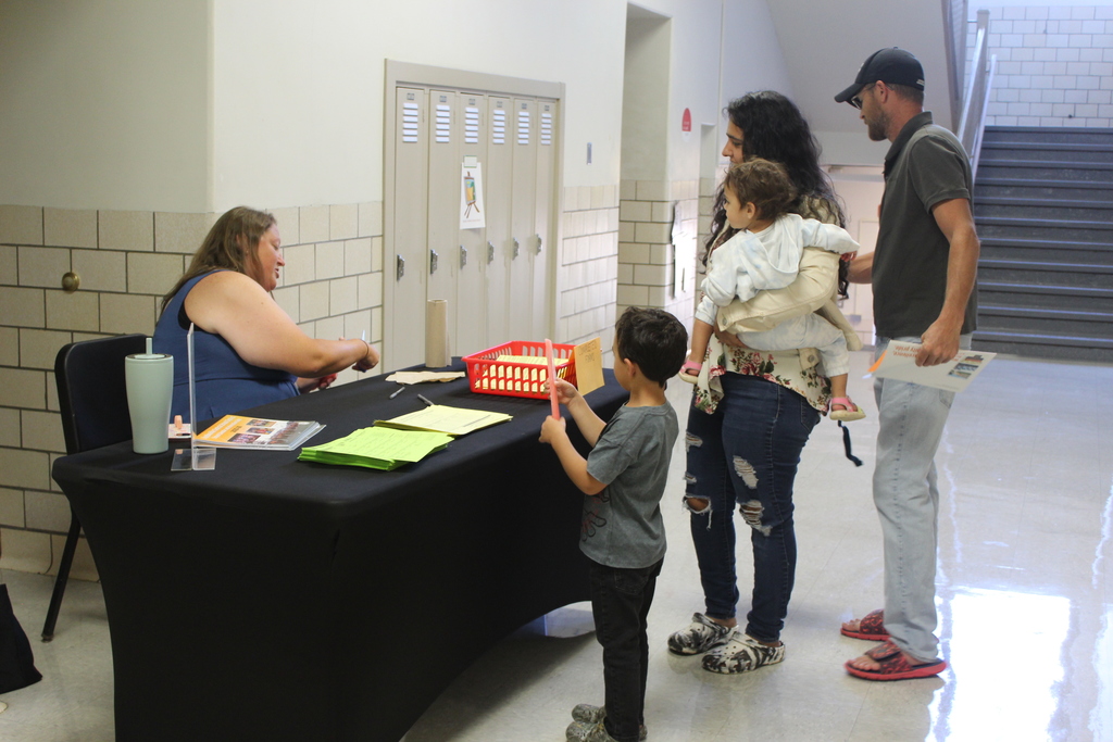 family standing near table receiving information from staff member