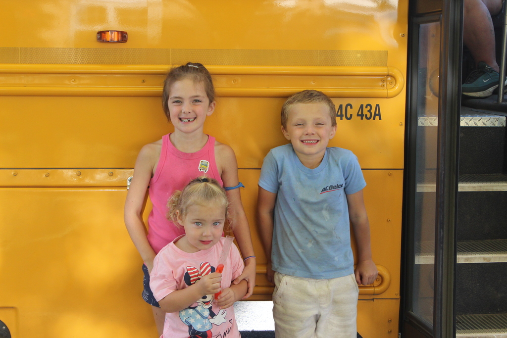 three kids in front of school bus