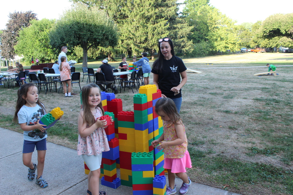 three girls and their mom building with supersize legos outside