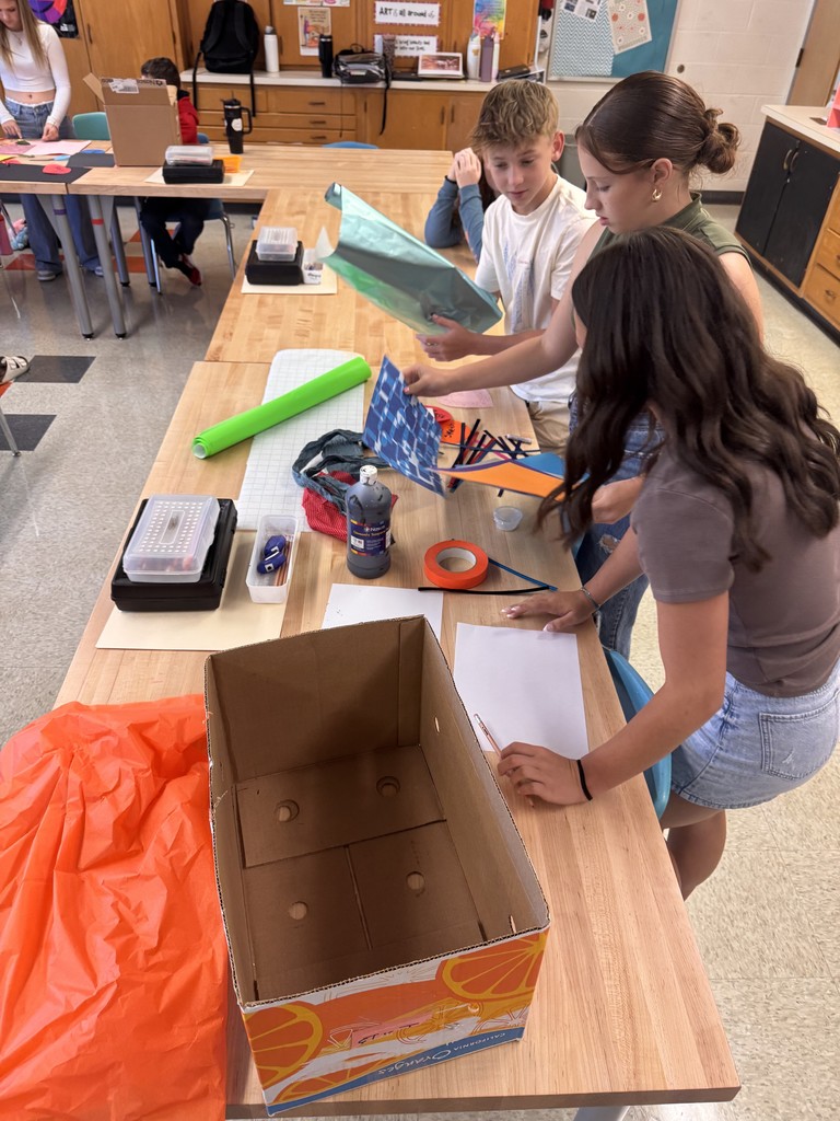 studios standing around a table in art class working with materials