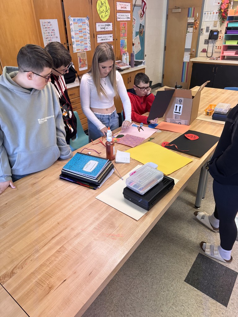 studios standing around a table in art class working with materials