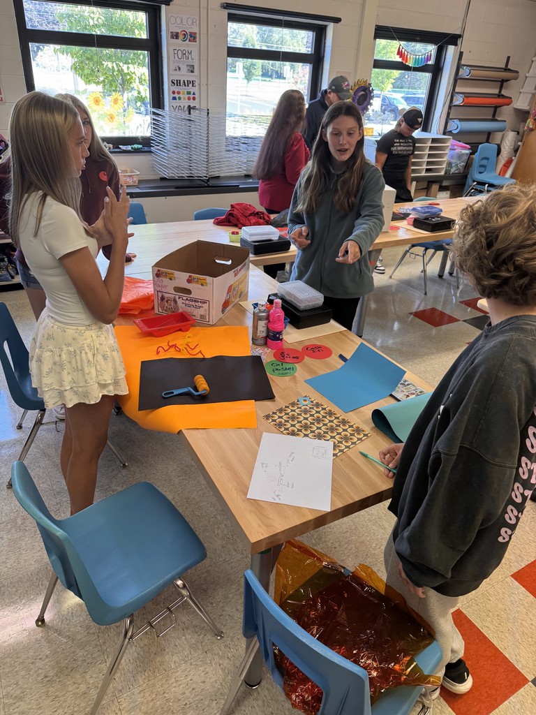 studios standing around a table in art class working with materials