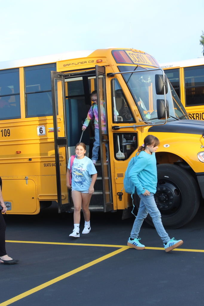 girl getting off the bus and another student walking in front of her