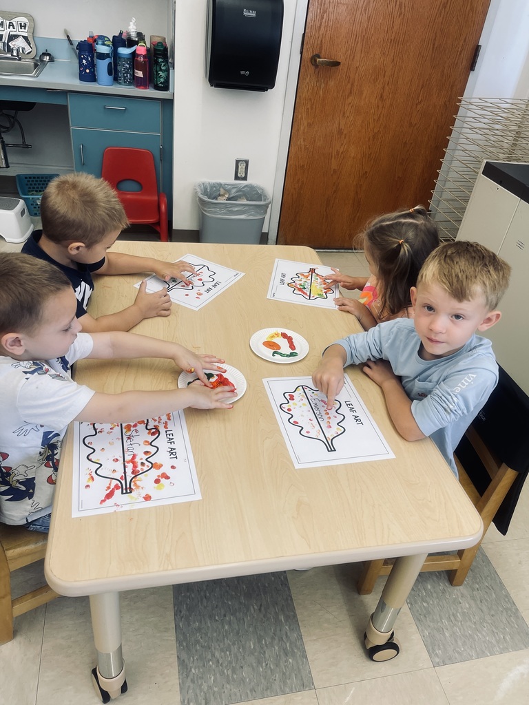 students sitting at table painting 
