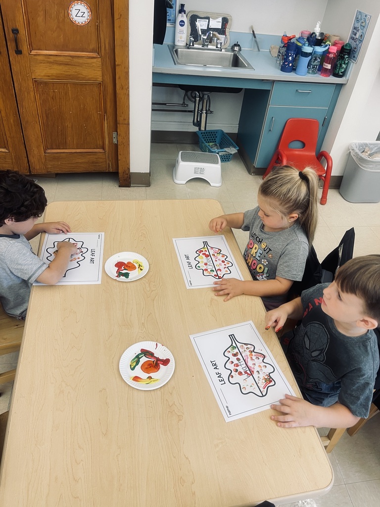 students sitting at table painting 
