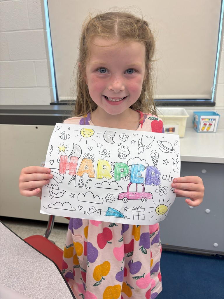 girl holding sheet of paper with her name on it