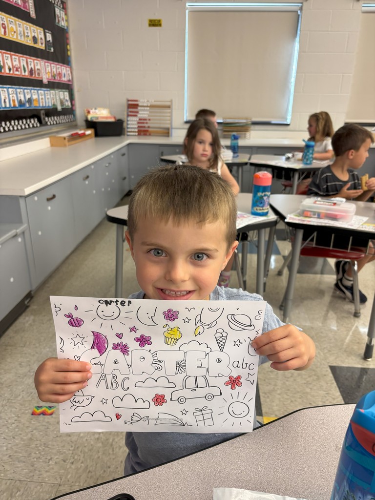 boy holding sheet of paper with his name on it