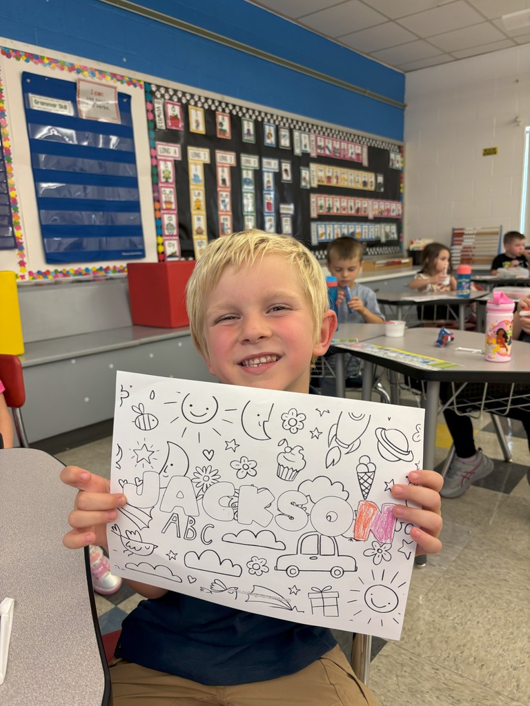 boy holding sheet of paper with his name on it