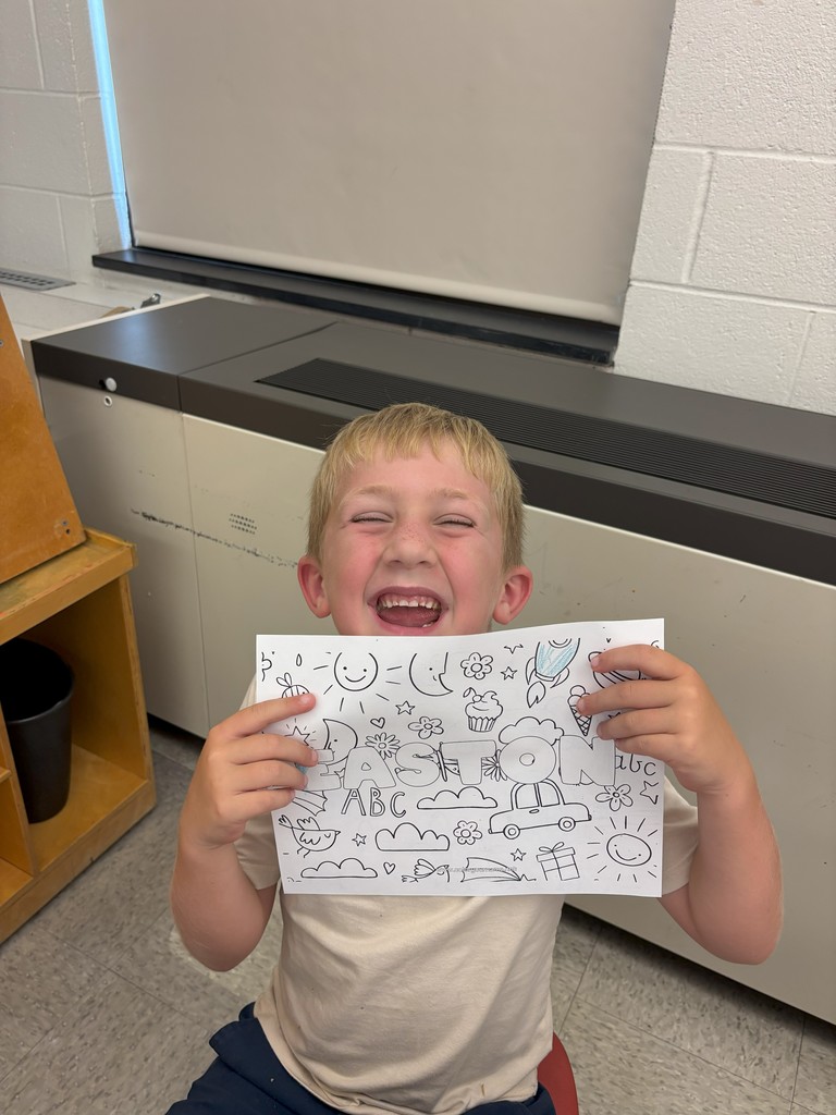 boy holding sheet of paper with his name on it