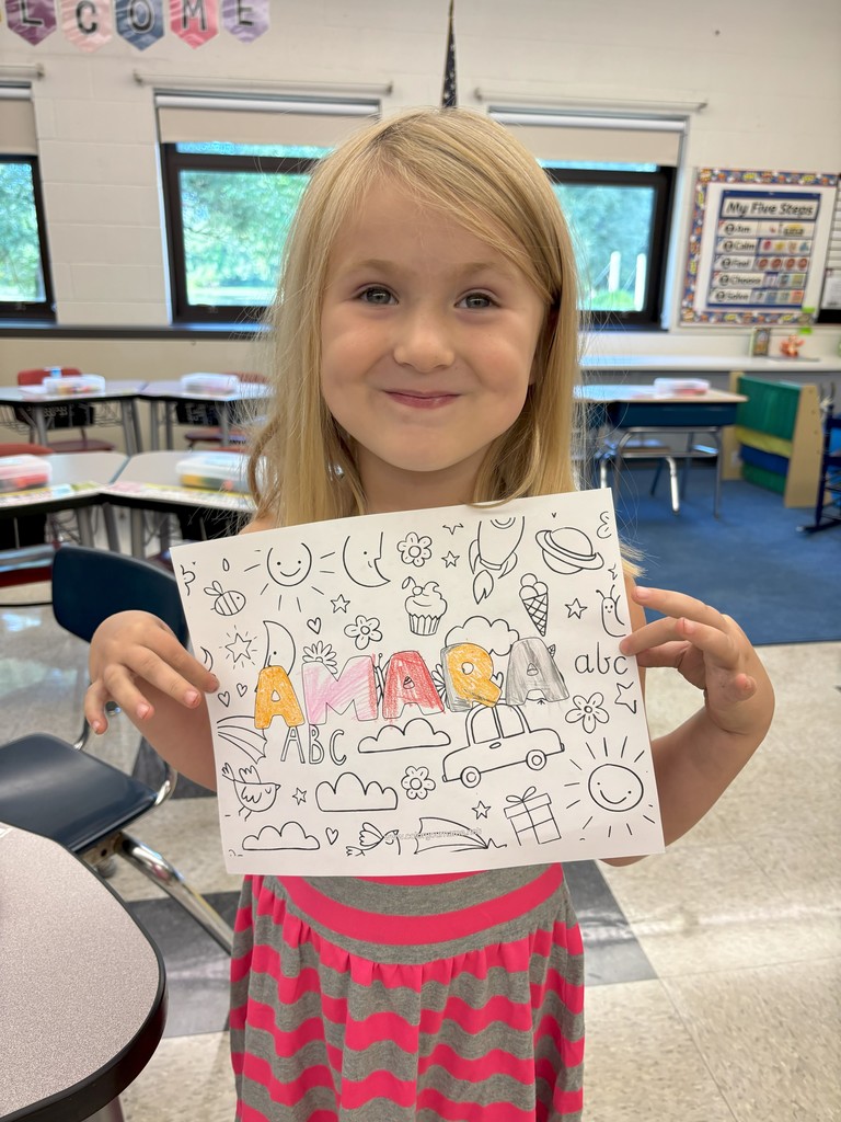 girl holding sheet of paper with her name on it