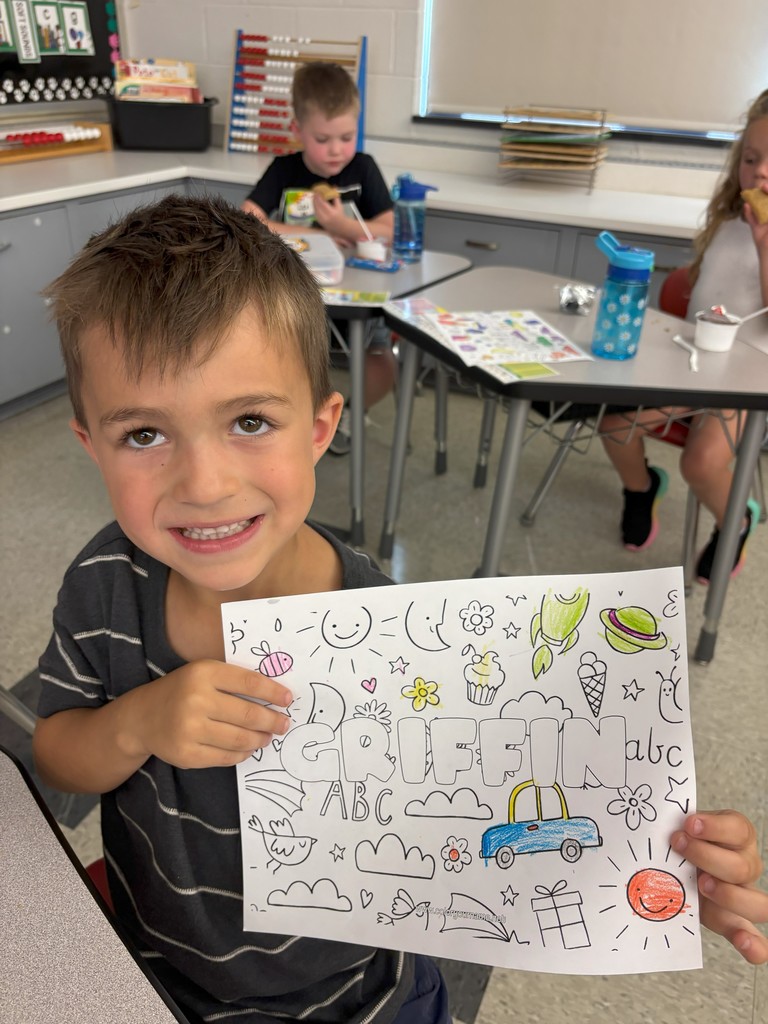 boy holding sheet of paper with his name on it