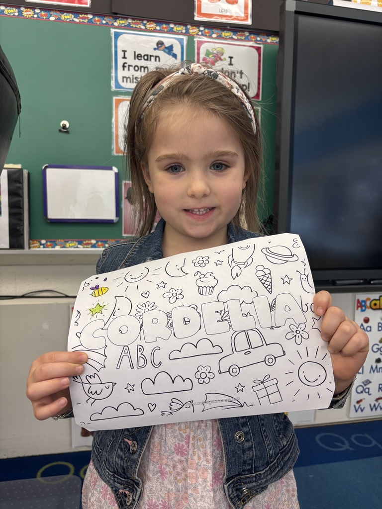 girl holding sheet of paper with her name on it