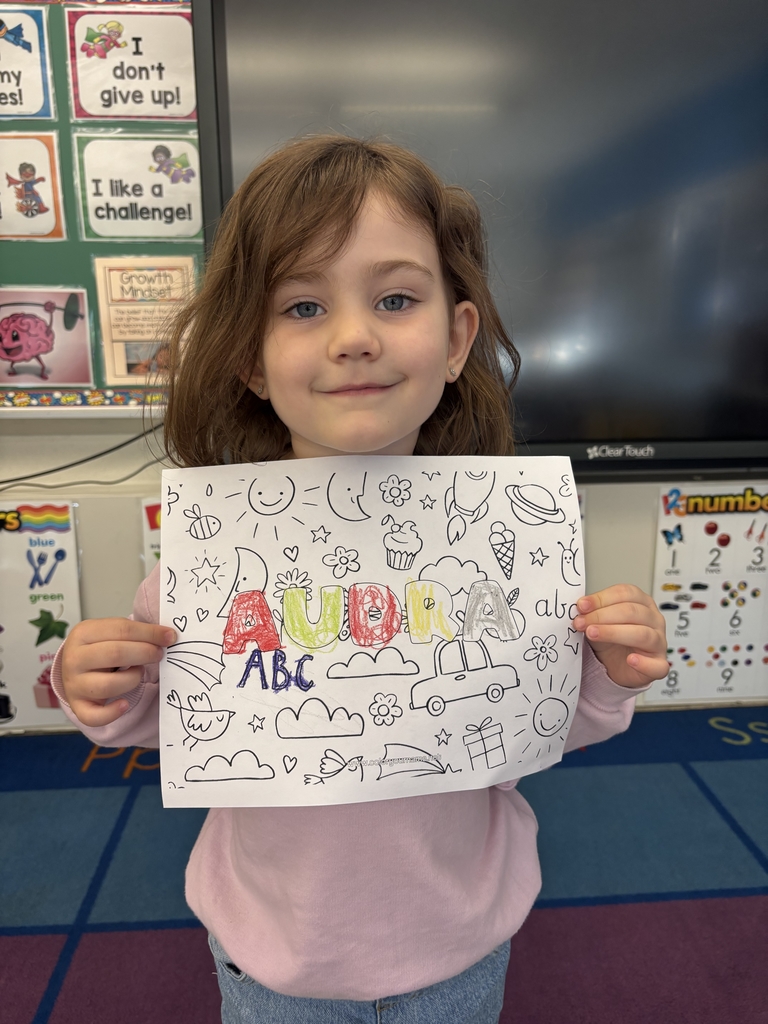 girl holding sheet of paper with her name on it