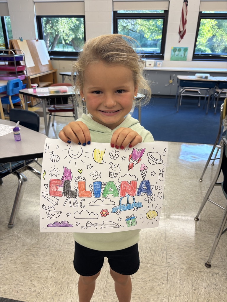 girl holding sheet of paper with her name on it