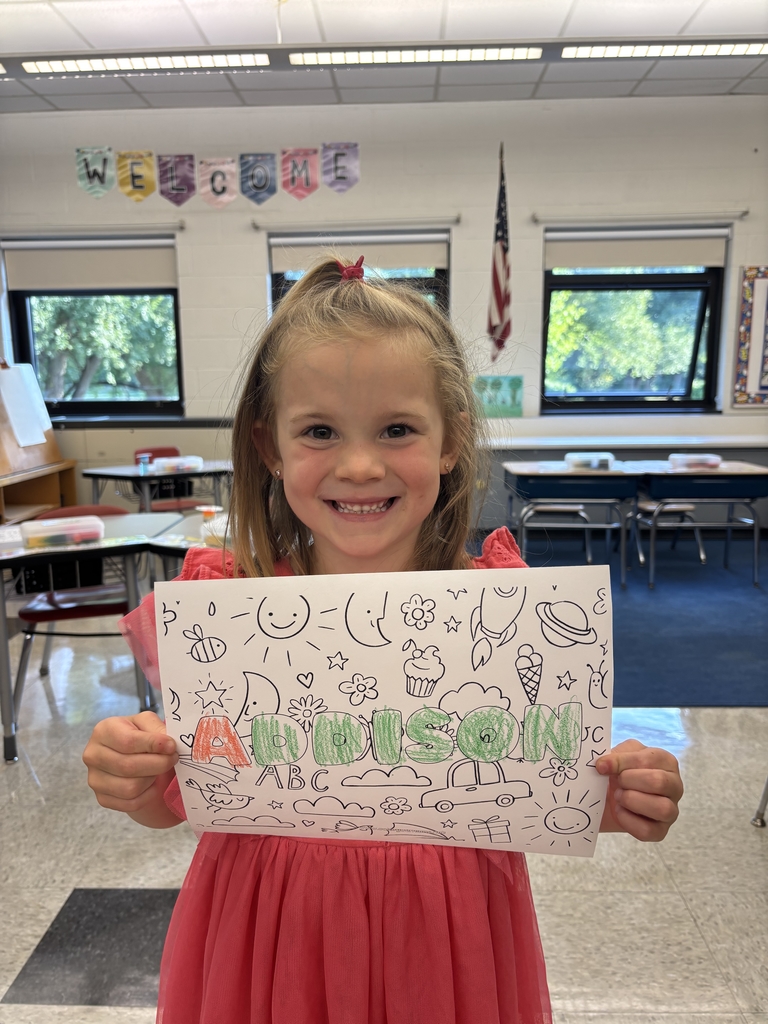 girl holding sheet of paper with her name on it