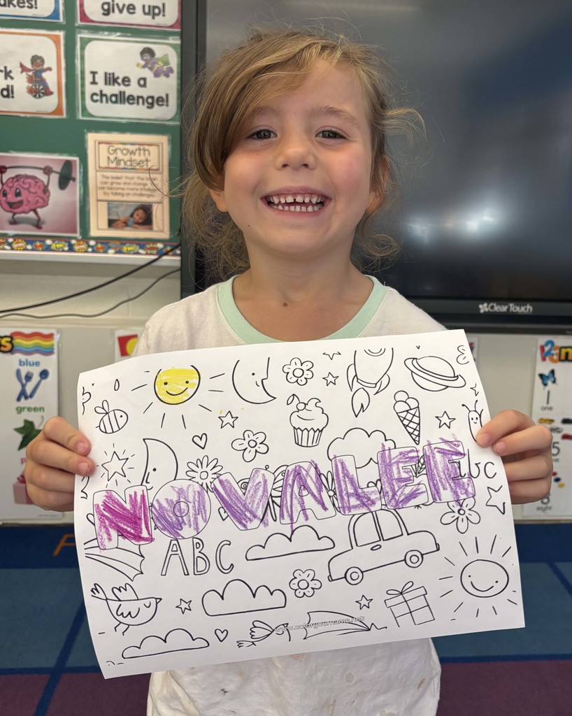 girl holding sheet of paper with her name on it