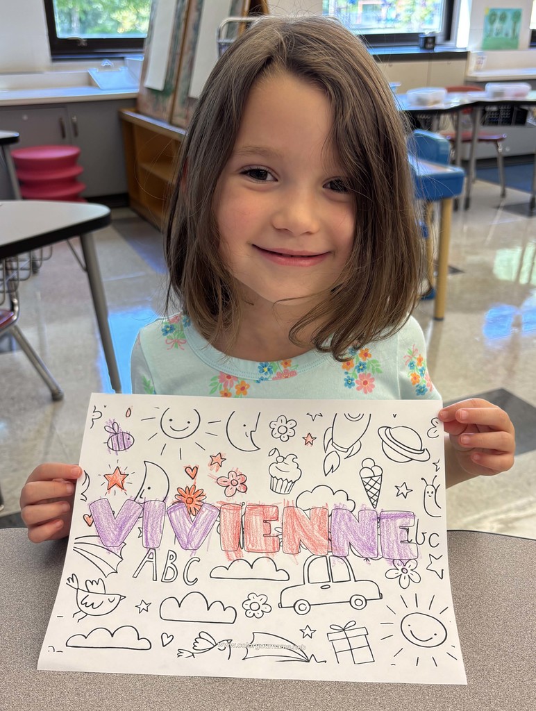 girl holding sheet of paper with her name on it