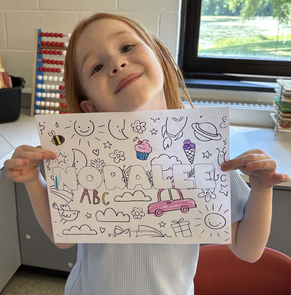 girl holding sheet of paper with her name on it