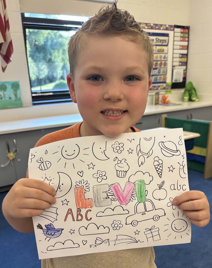 boy holding sheet of paper with his name on it