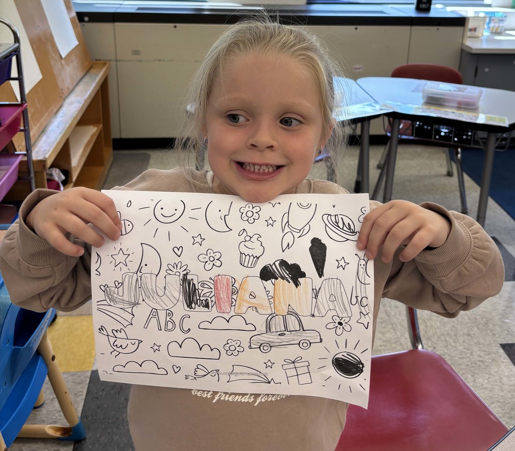 girl holding sheet of paper with her name on it