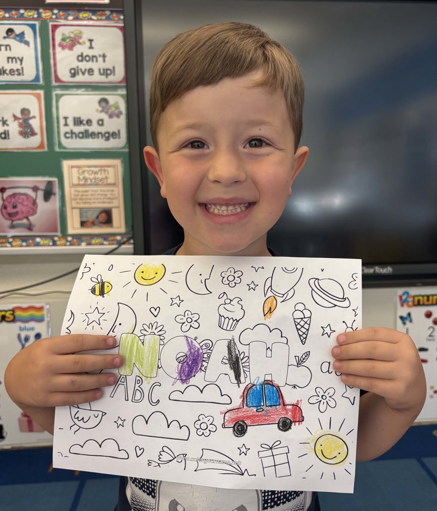 boy holding sheet of paper with his name on it