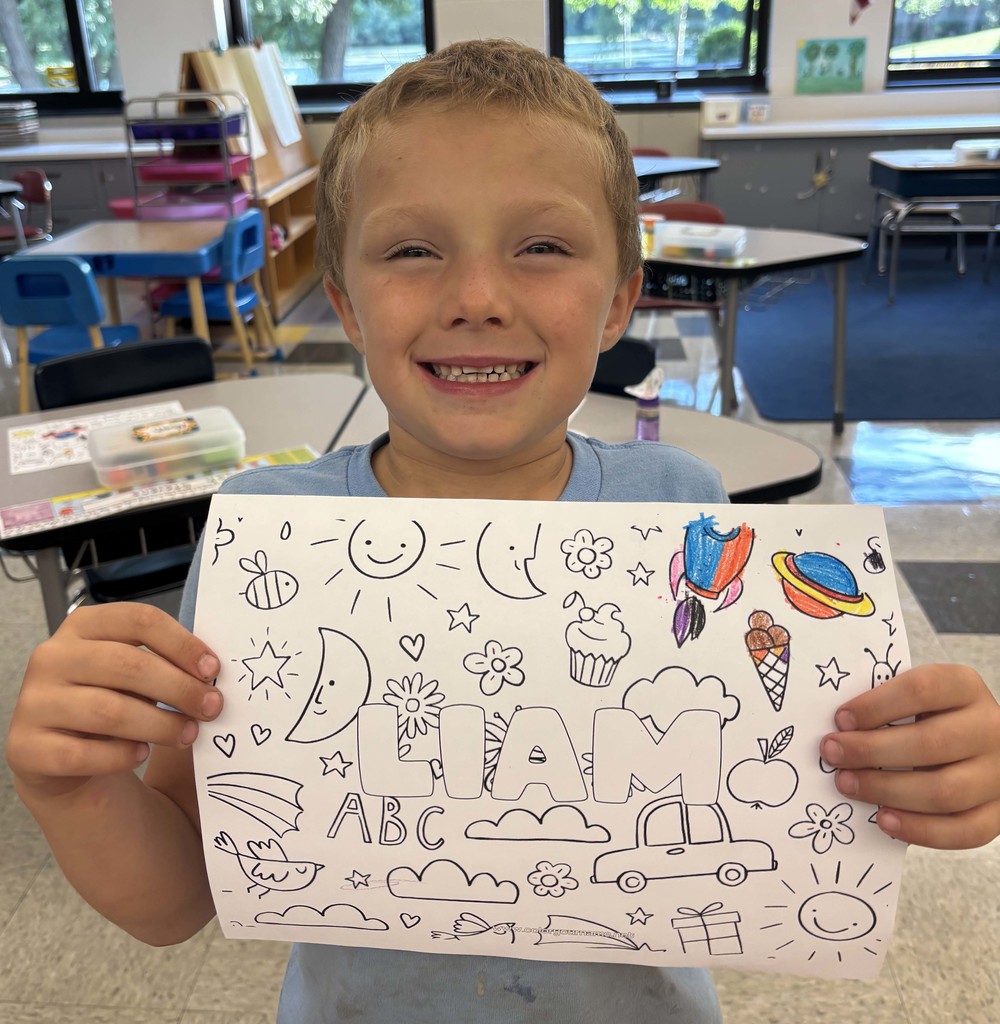 boy holding sheet of paper with his name on it