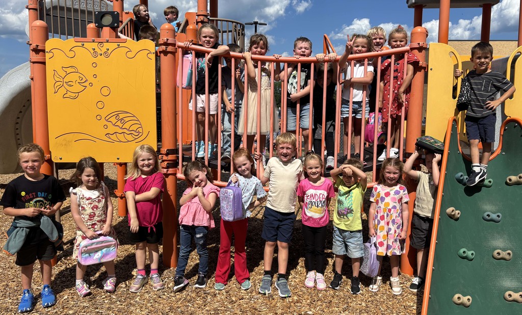 kindergarteners posing for a group photo on the playground equipment