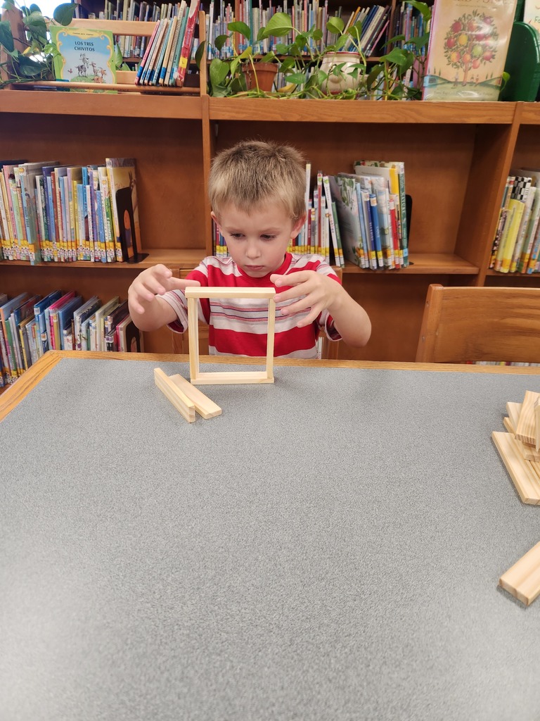 boy sitting at table building with wooden blocks