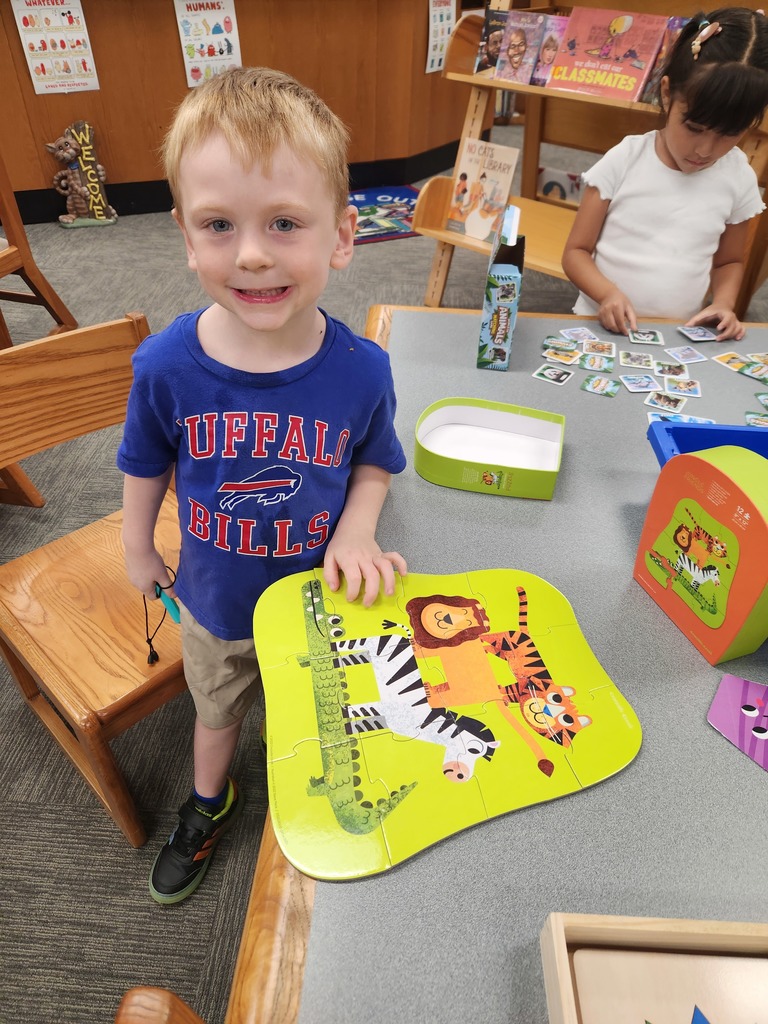 a boy with a completed puzzle on the table and a girl playing with cards on the table