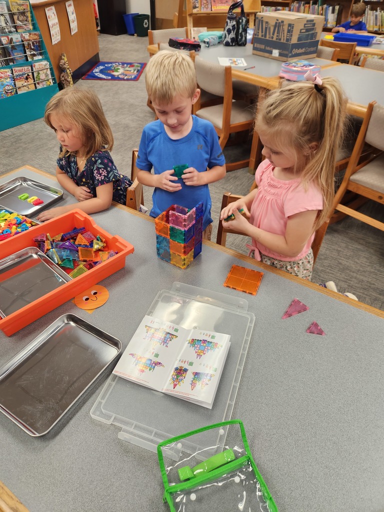 three students playing with shapes at table