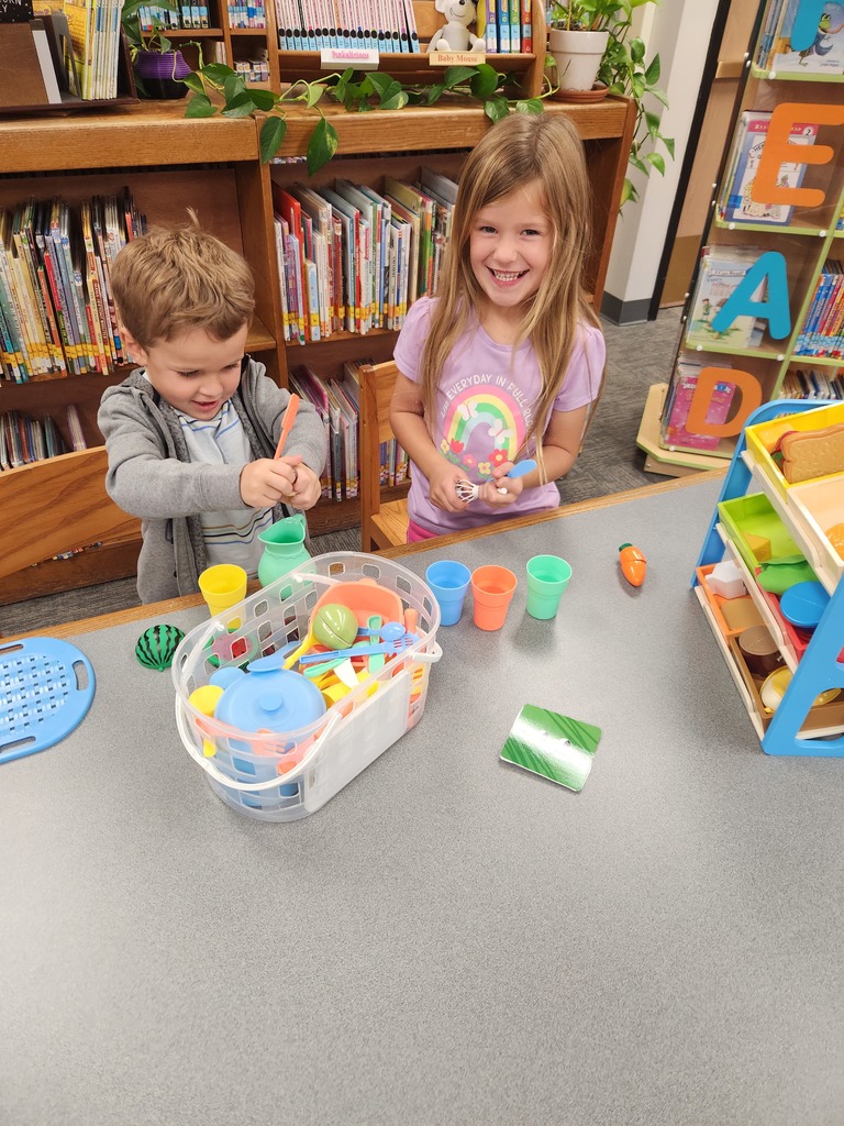two students playing at a table with cups