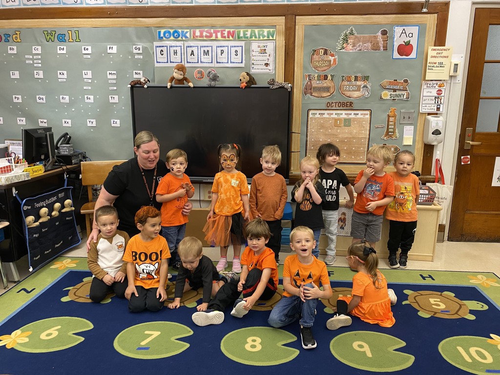 group of students wearing orange and black with their teacher