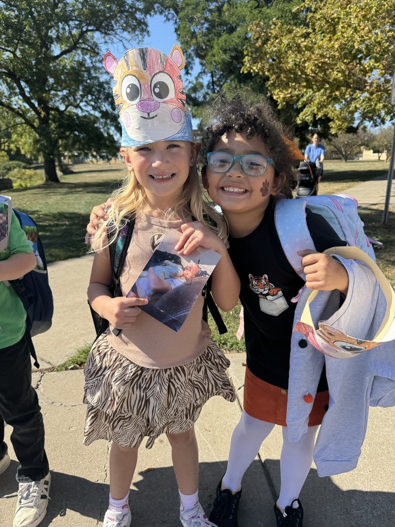 two students standing on sidewalk waiting for parade