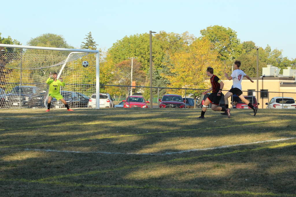 boys shooting soccer ball on goal