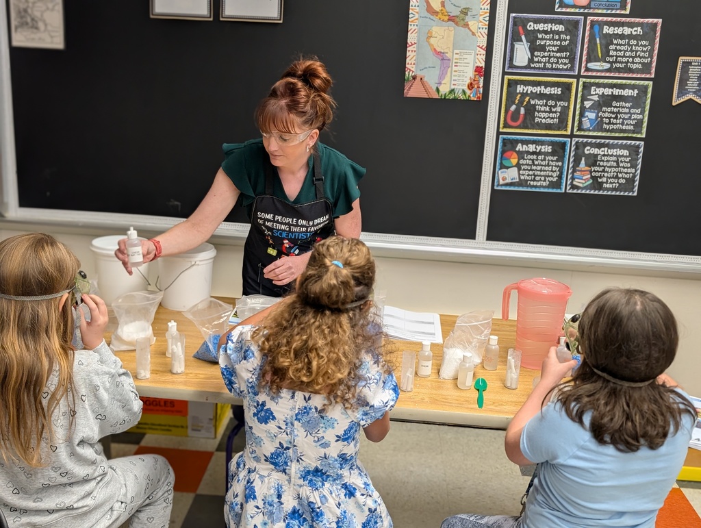 teacher demonstrating to science students seated at table