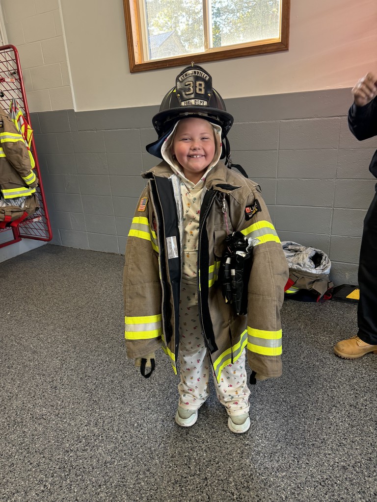 student trying on fireman's jacket and helmet