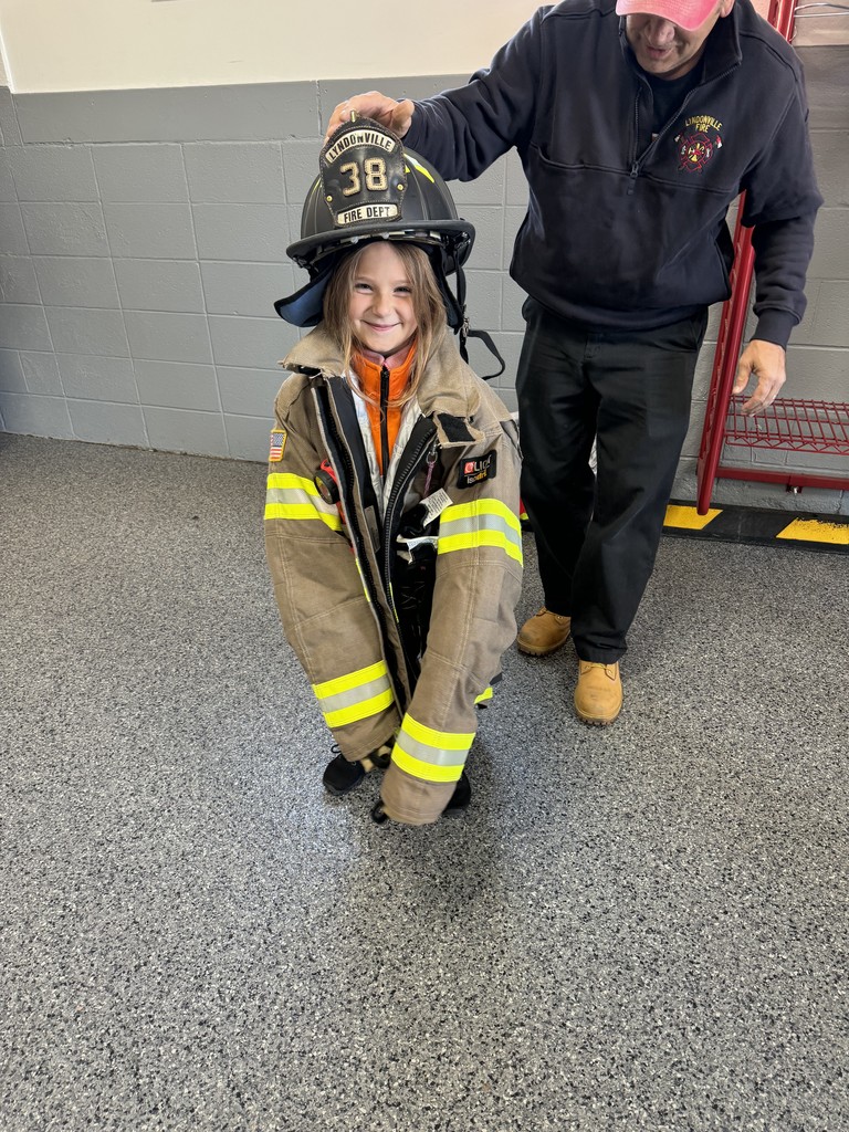 student trying on fireman's jacket and helmet