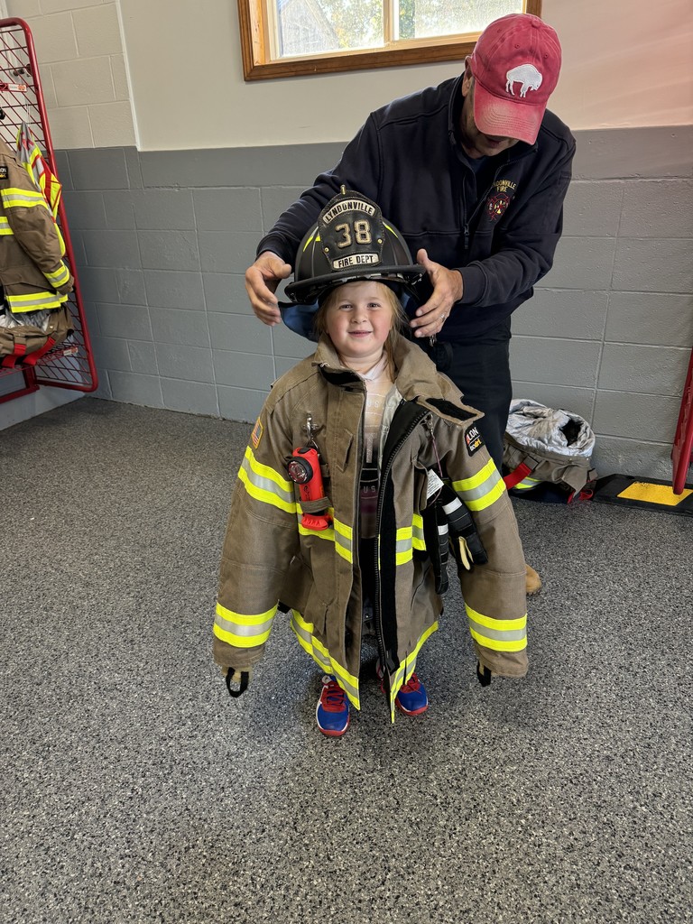 student trying on fireman's jacket and helmet