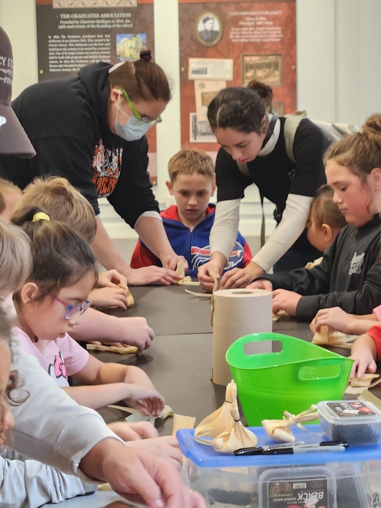 adults helping students make corn dolls