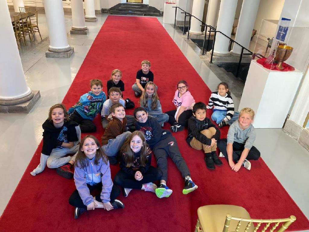 students sitting on rug in museum